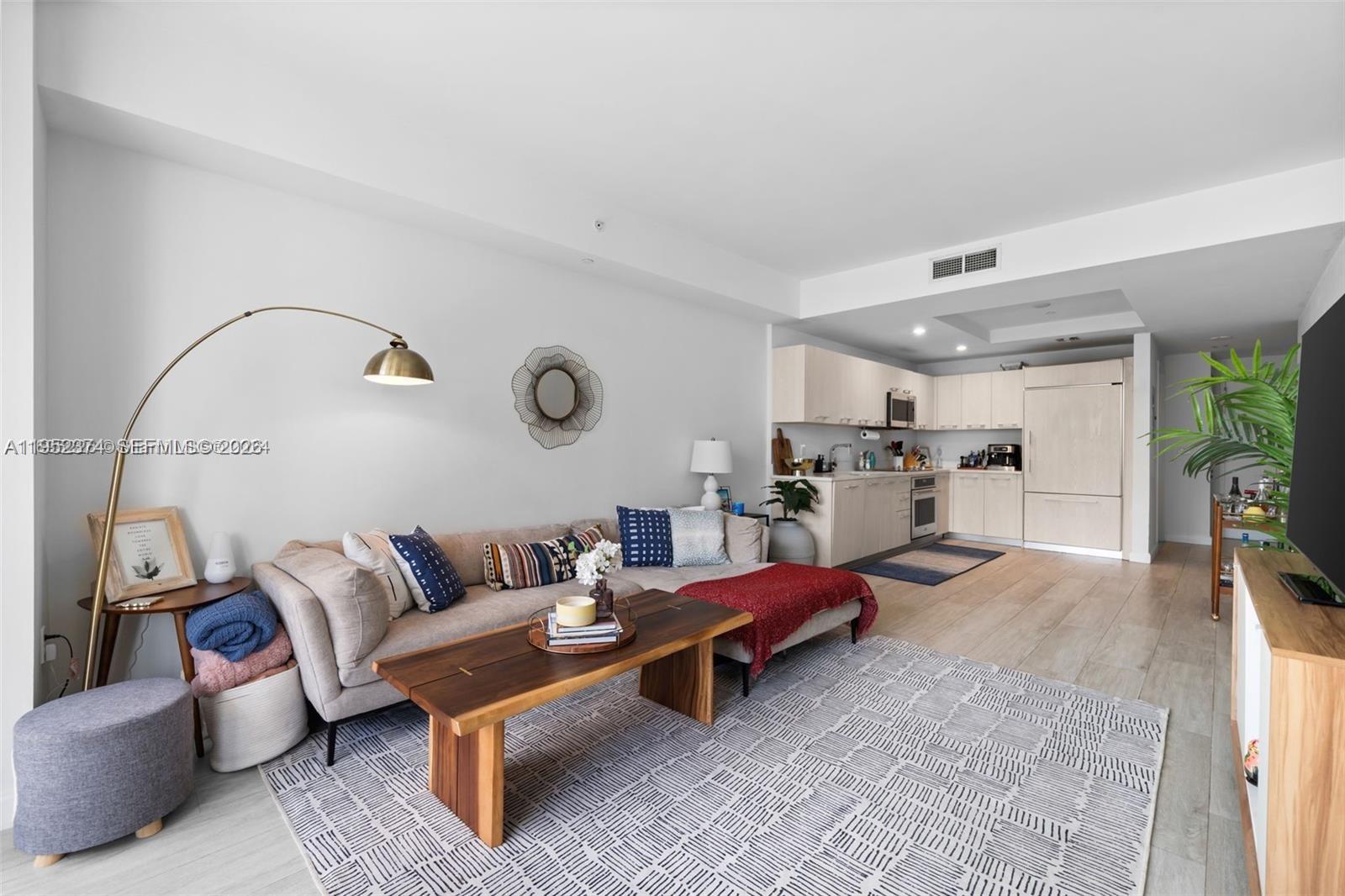 A living room with a sectional sofa, wooden coffee table, and an open-concept kitchen — 55 SW 9th St # 2305, Miami FL 33130, MIAMI, FL