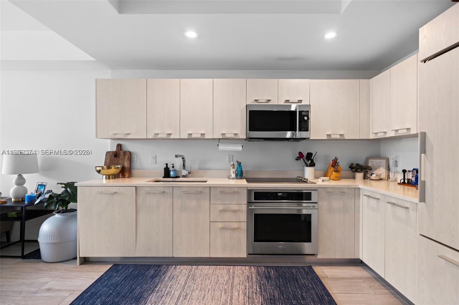 A modern kitchen features light wood cabinets, stainless steel appliances, and a blue area rug — 55 SW 9th St # 2305, Miami FL 33130, MIAMI, FL