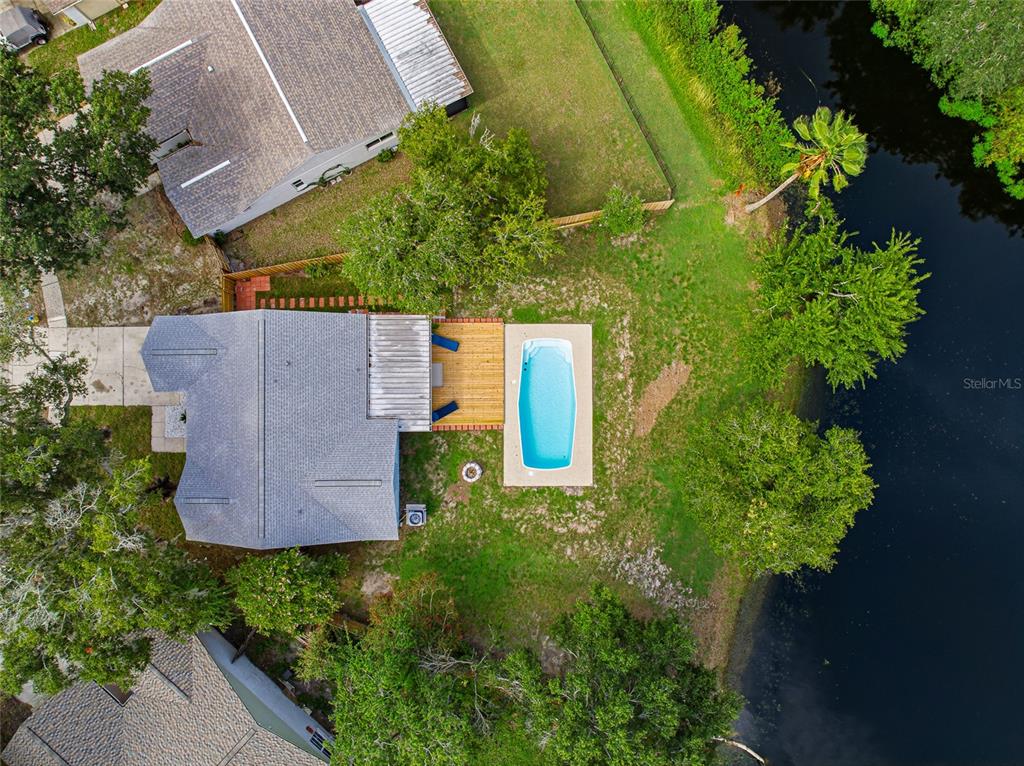 A backyard with a swimming pool, a wooden deck, and a light blue house exterior — 4637 CABBAGE PALM DRIVE, VALRICO, FL