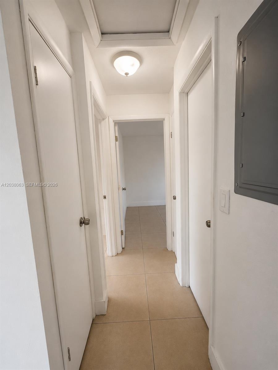 A narrow hallway features white doors, light-colored tile flooring, and a ceiling-mounted light fixture — 1857 NW 46th St # 1857, Miami FL 33142, MIAMI, FL