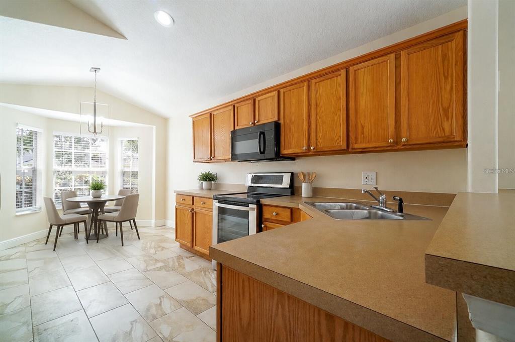 A kitchen with wood cabinets, laminate countertops, and a dining area with a bay window — 13518 BRIARMOOR COURT, ORLANDO, FL