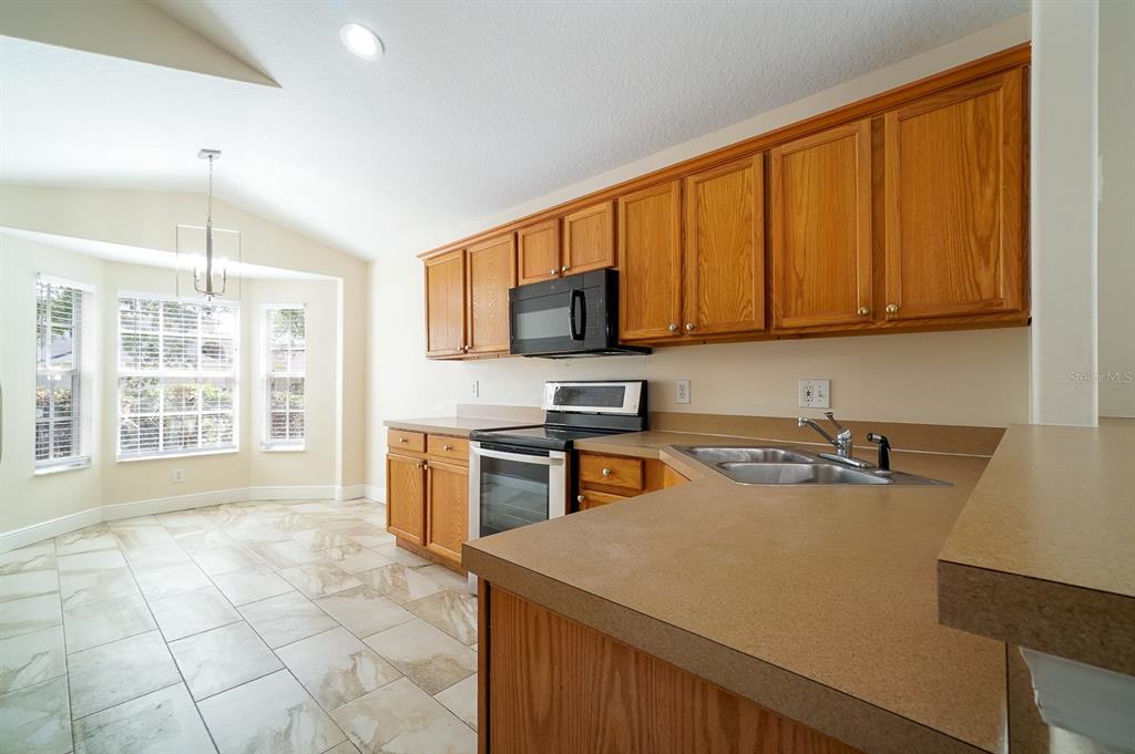 A kitchen with oak cabinets, laminate countertops, stainless steel appliances, and tile flooring — 13518 BRIARMOOR COURT, ORLANDO, FL