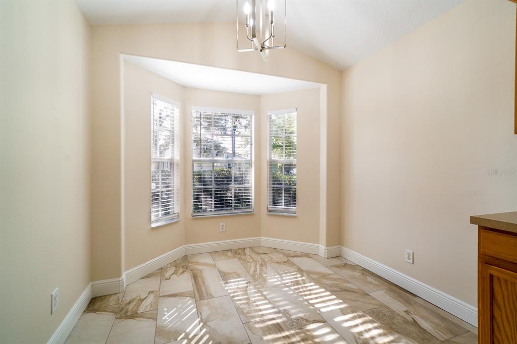 A dining nook with a vaulted ceiling, bay windows, and light-colored tile flooring — 13518 BRIARMOOR COURT, ORLANDO, FL