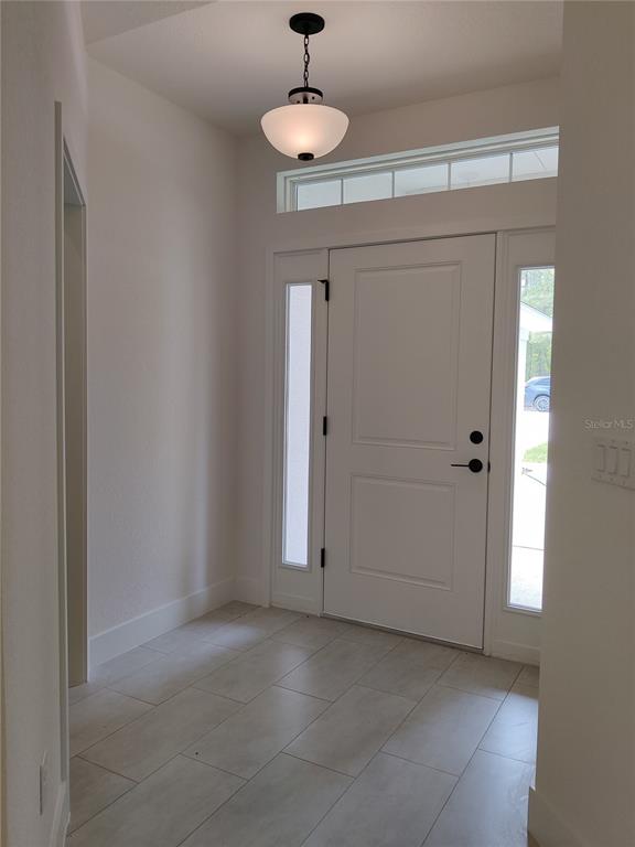 A bright entryway features a white front door with sidelights, a transom window, and tile flooring — 15406 SCAUP DUCK AVENUE, WEEKI WACHEE, FL