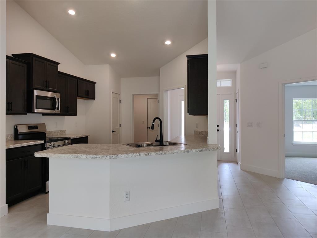 A kitchen features dark cabinets, a peninsula with a sink, and light-colored countertops — 15406 SCAUP DUCK AVENUE, WEEKI WACHEE, FL