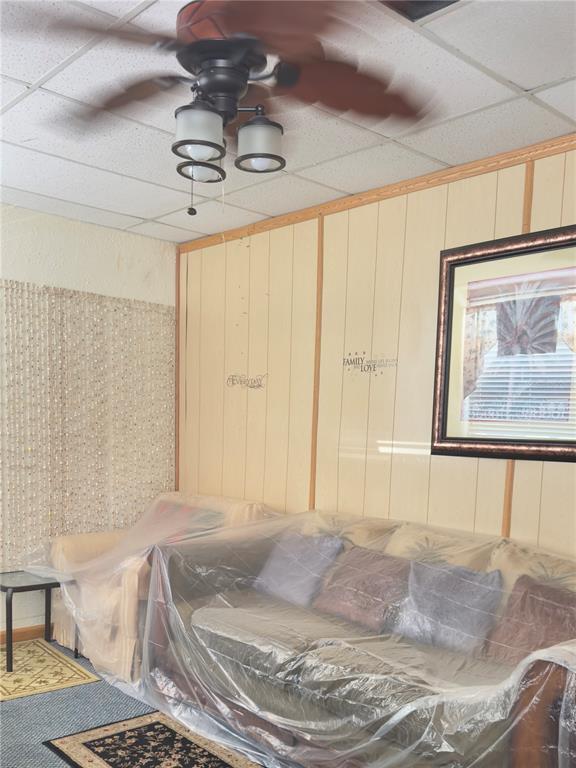 A living room with wood-paneled walls, a ceiling fan, and furniture covered in plastic — 1275 N BANANA RIVER DRIVE, MERRITT ISLAND, FL