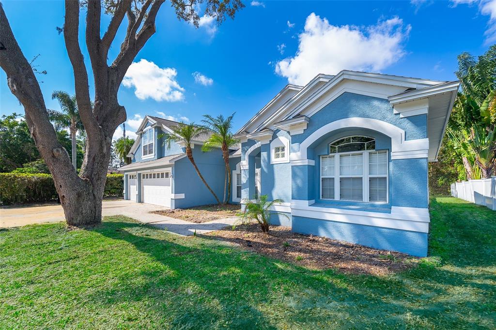 A blue single-story house with white trim, a two-car garage, and a large front tree — 8119 LAKE CROWELL CIRCLE, ORLANDO, FL