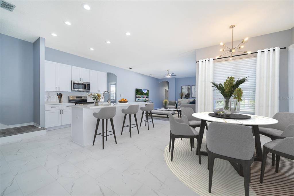 A modern open-concept kitchen and dining area with white cabinetry, a kitchen island, and tile flooring — 8119 LAKE CROWELL CIRCLE, ORLANDO, FL