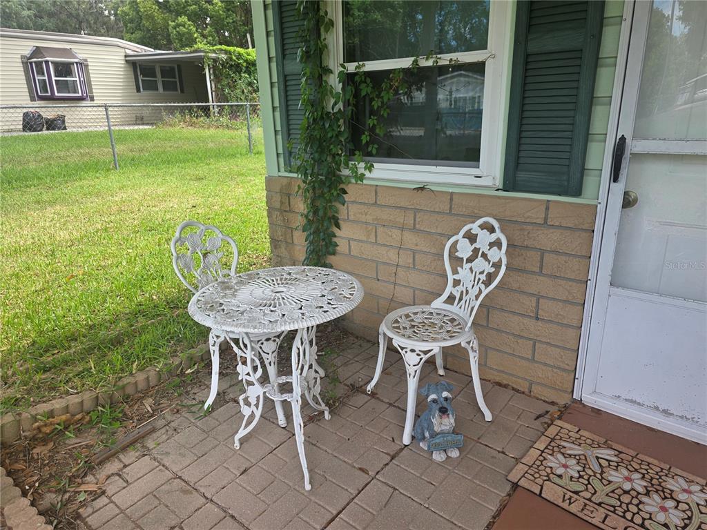 A small patio features a white metal bistro set and a decorative dog figurine — 16920 SE 101ST AVENUE ROAD, SUMMERFIELD, FL