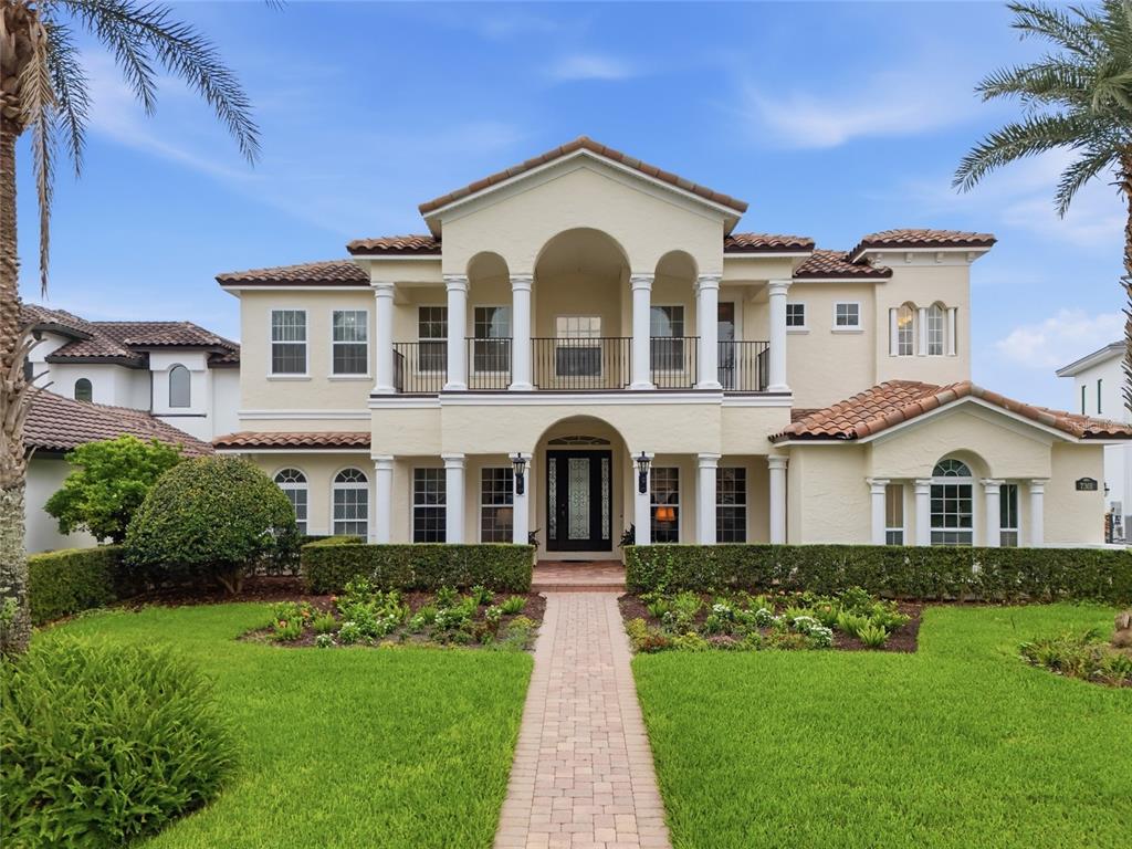 A two-story Mediterranean-style house with a tiled roof, white columns, and a brick walkway — 7301 WILD BLACKBERRY TRAIL, WINTER GARDEN, FL