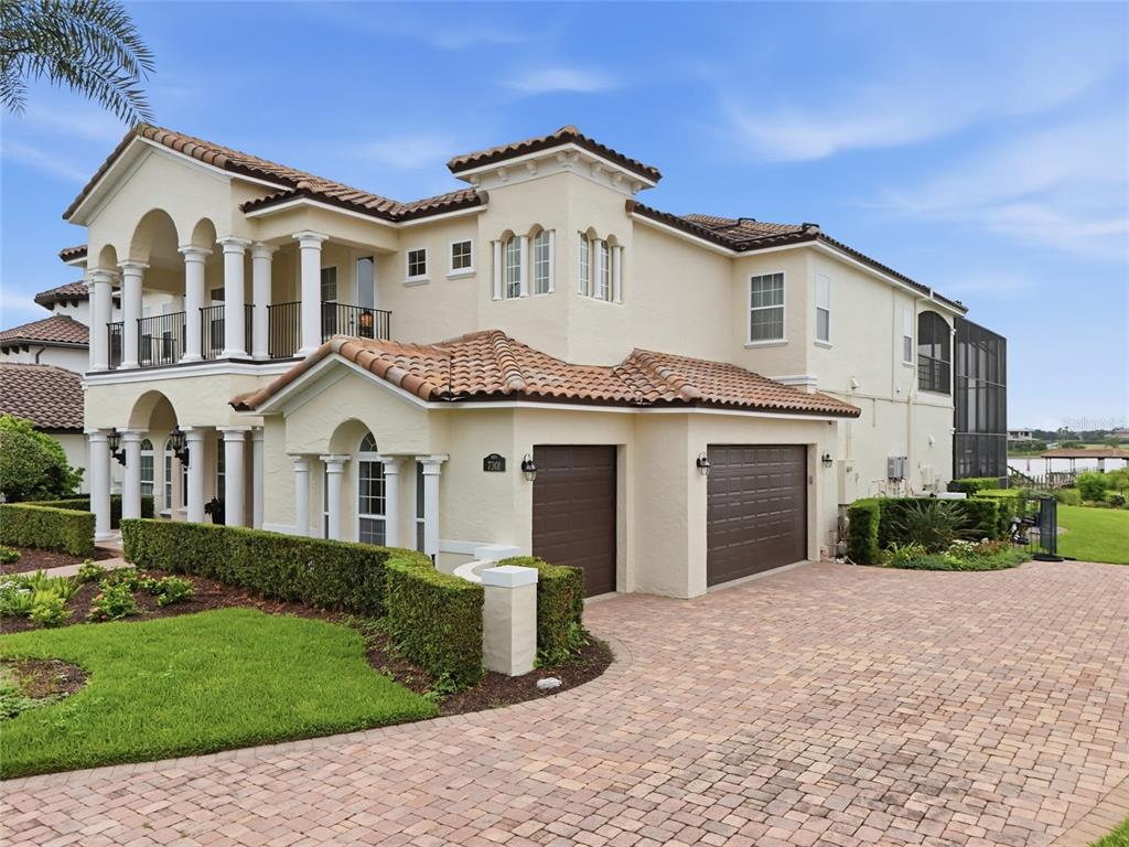A two-story Mediterranean-style house with a tile roof, two-car garage, and brick paver driveway — 7301 WILD BLACKBERRY TRAIL, WINTER GARDEN, FL