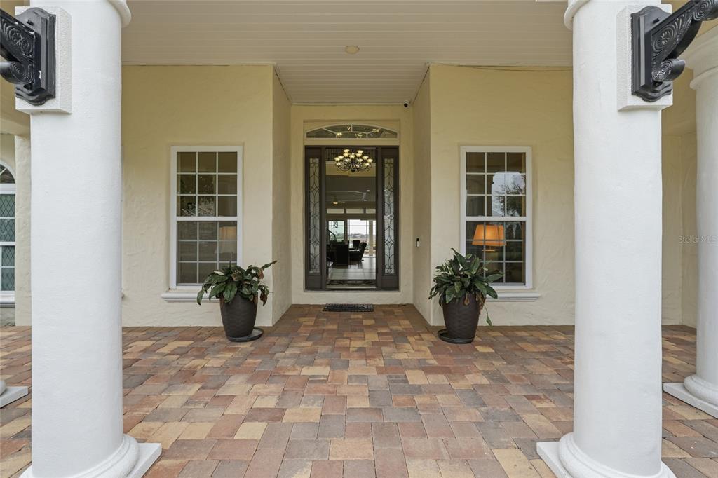 A covered entryway features two white columns, a paver floor, and a dark front door — 7301 WILD BLACKBERRY TRAIL, WINTER GARDEN, FL