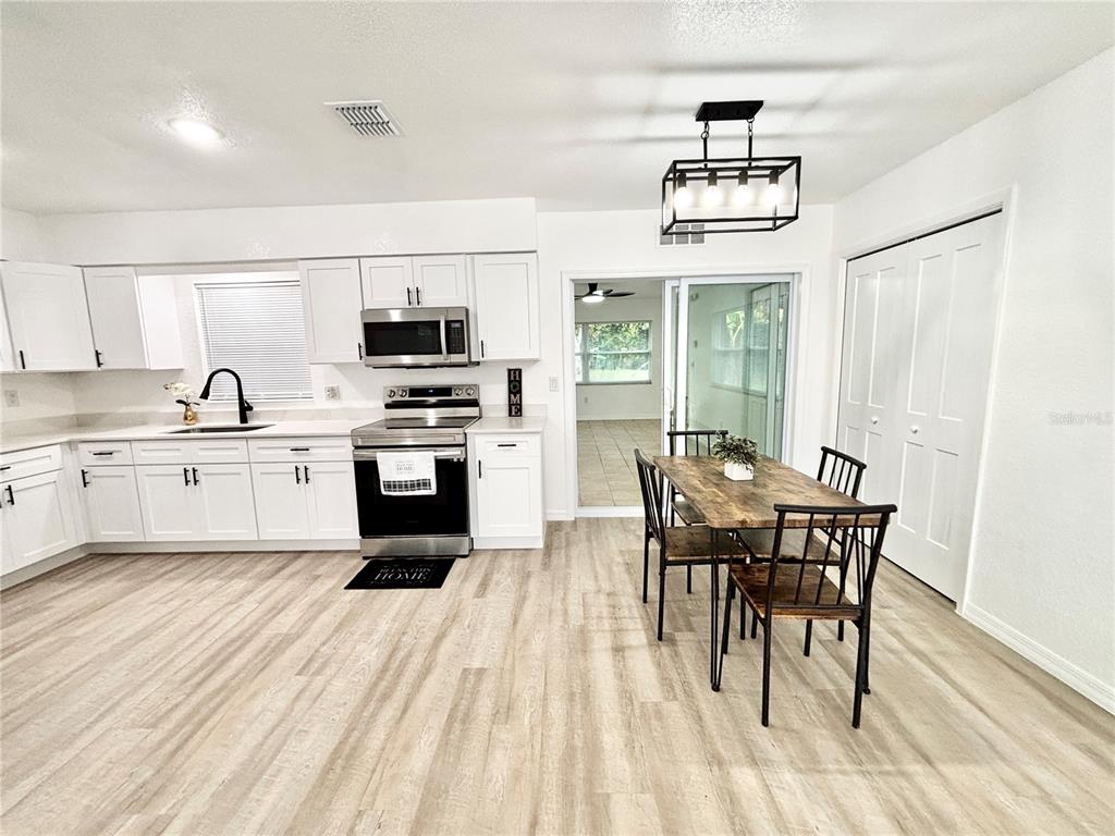 A kitchen with white cabinets, stainless steel appliances, and a dining table with four chairs — 1516 AVENUE D NE, WINTER HAVEN, FL