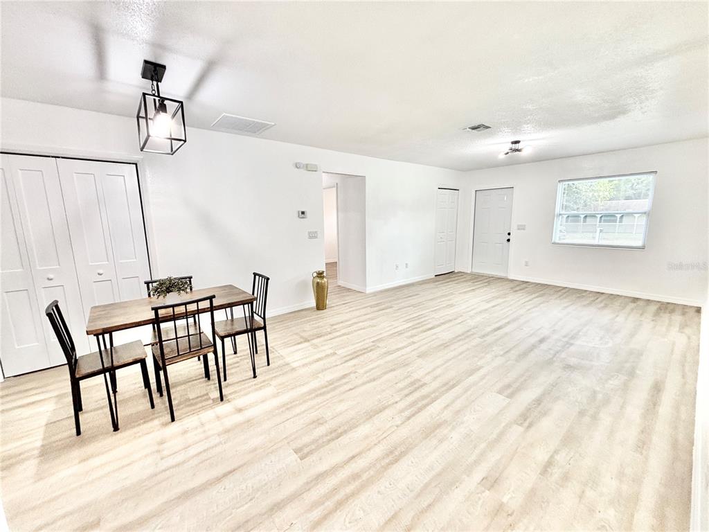 A dining area with a wooden table and chairs sits in a bright, open room — 1516 AVENUE D NE, WINTER HAVEN, FL