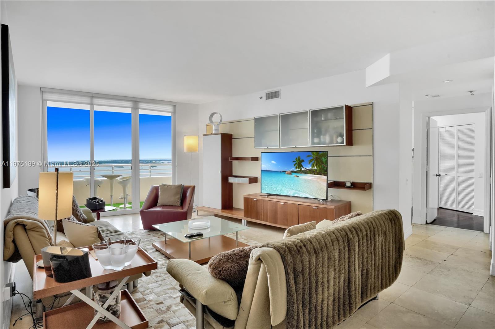 A living room features a television wall unit, glass coffee table, and balcony with water views — 808 Brickell Key Dr # 2506, Miami FL 33131, MIAMI, FL
