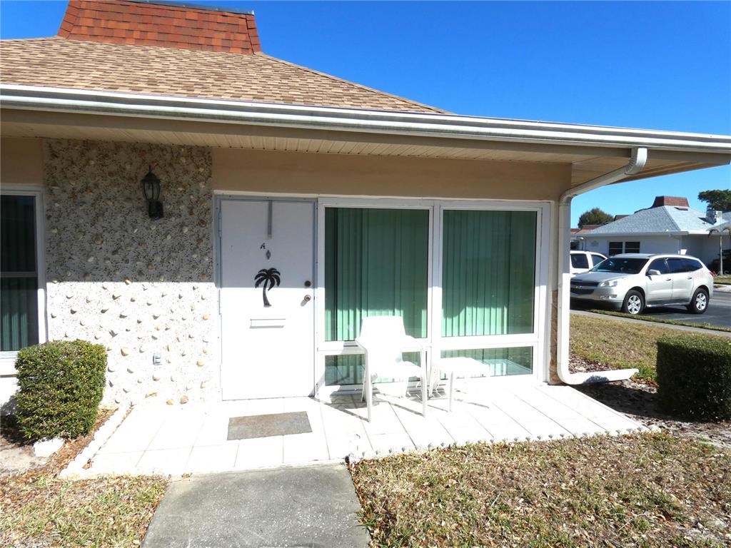 A white door with a palm tree decal sits beside a large window on a patio — 4324 TAHITIAN GARDENS CIRCLE UNIT A, HOLIDAY, FL