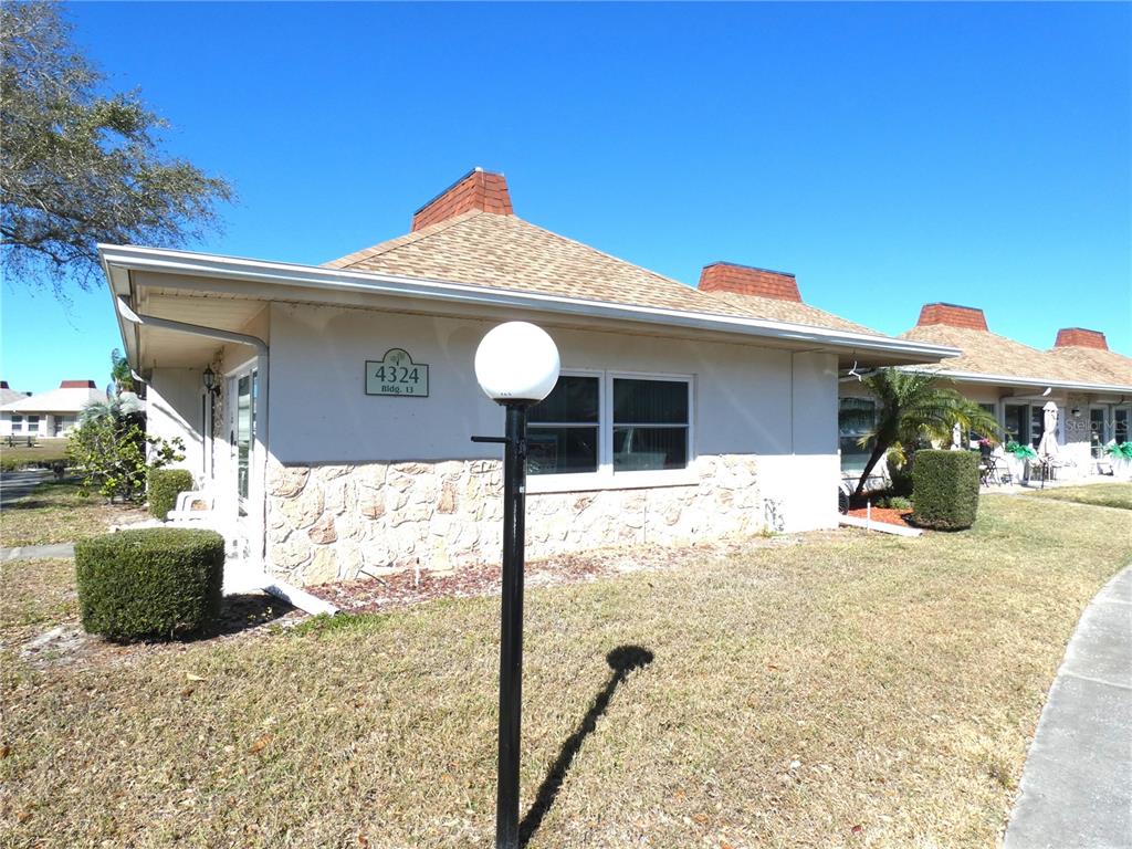 A single-story building with a stone facade, tan siding, and a shingled roof — 4324 TAHITIAN GARDENS CIRCLE UNIT A, HOLIDAY, FL