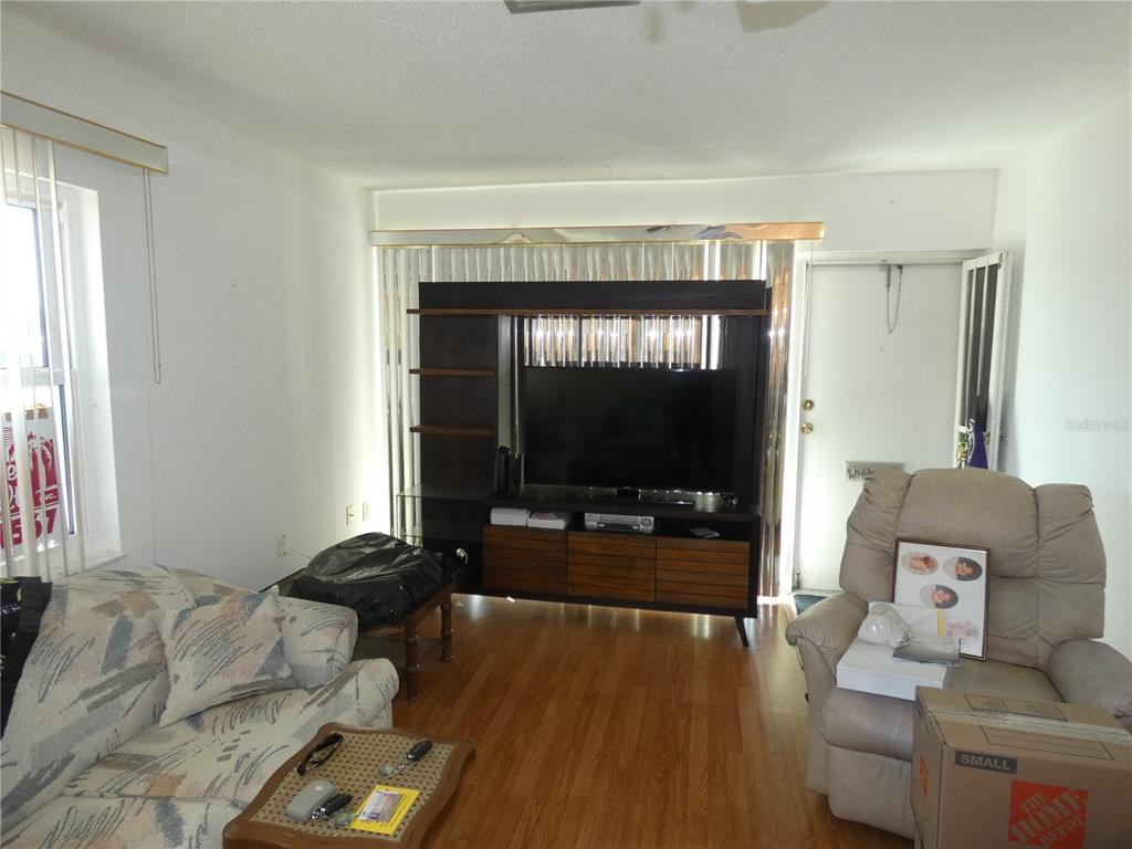 A living room features wood flooring, a large entertainment center, and a beige recliner — 4324 TAHITIAN GARDENS CIRCLE UNIT A, HOLIDAY, FL