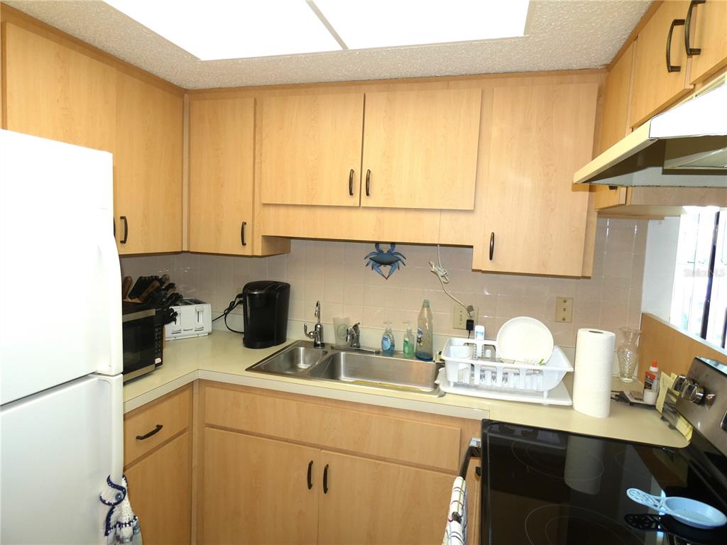 A kitchen with light wood cabinets, a double sink, and white appliances — 4324 TAHITIAN GARDENS CIRCLE UNIT A, HOLIDAY, FL