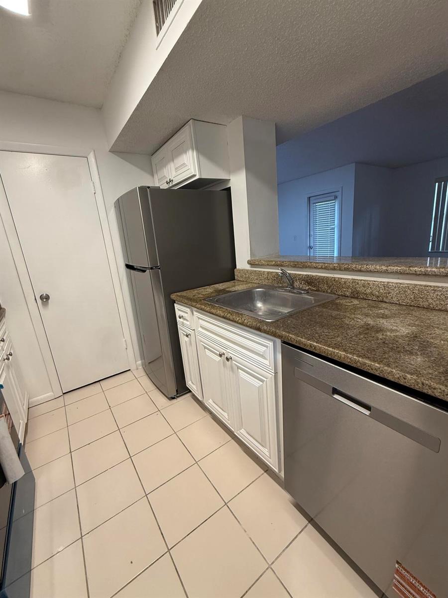 A kitchen features white cabinets, granite countertops, stainless steel appliances, and light-colored tile flooring — 4341 W Mcnab Road # 22, Pompano Beach FL 33069, POMPANO BEACH, FL