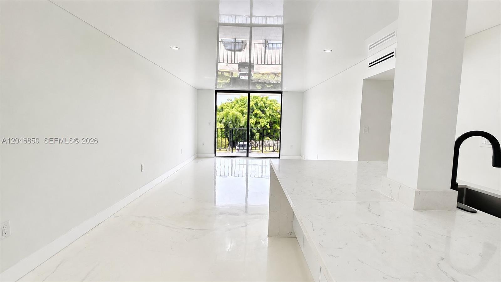 A minimalist white kitchen and living area features glossy floors and a balcony view — 9682 Fontainebleau Blvd # 203, Miami FL 33172, MIAMI, FL