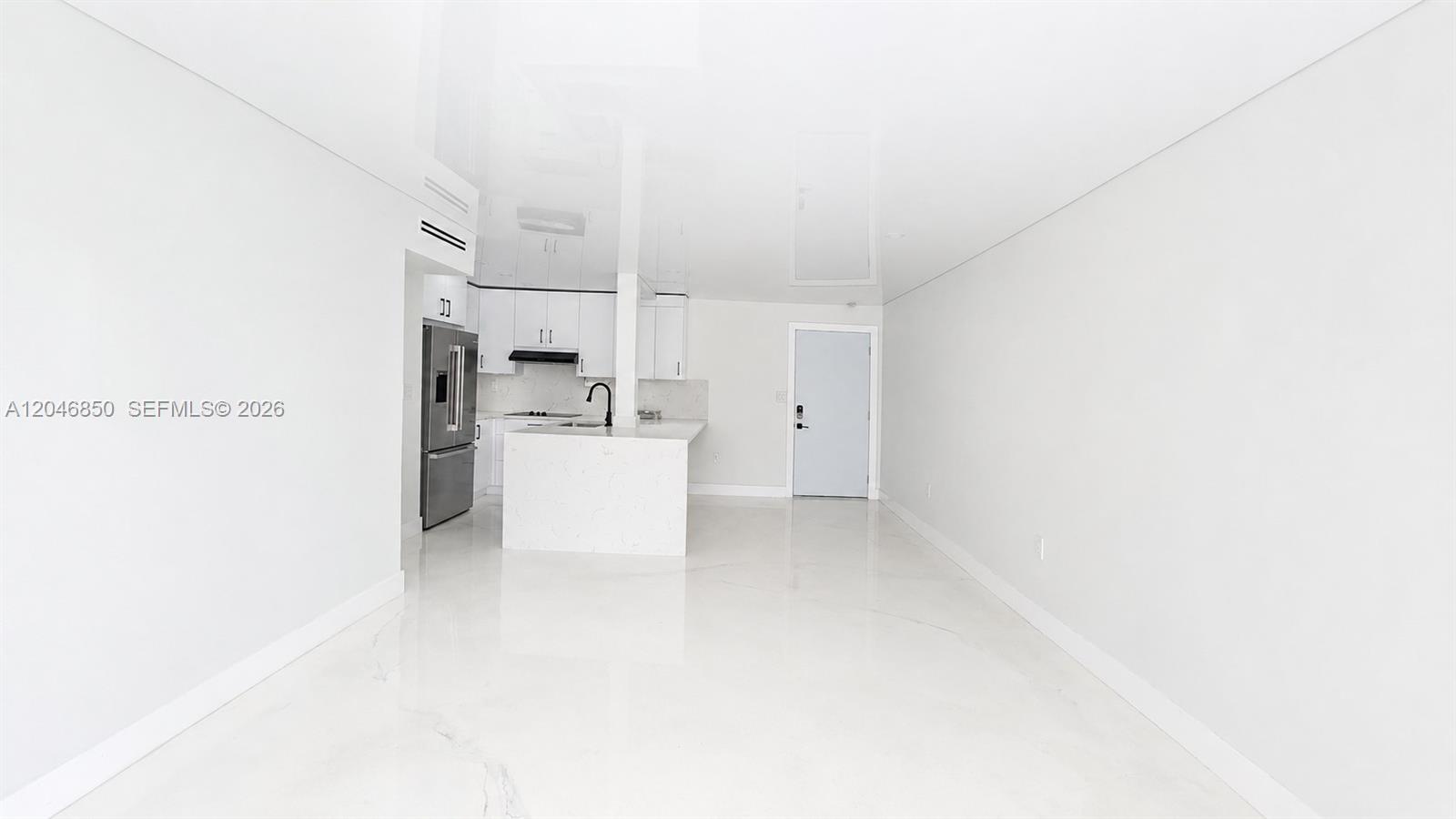 A minimalist kitchen with white cabinets and a marble island opens into a bright room — 9682 Fontainebleau Blvd # 203, Miami FL 33172, MIAMI, FL