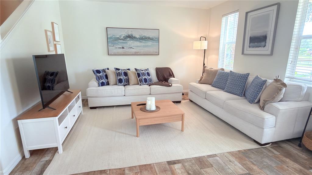 A living room features two white sofas, a wooden coffee table, and a television console — 3880 82ND AVENUE CIRCLE E UNIT 101, SARASOTA, FL