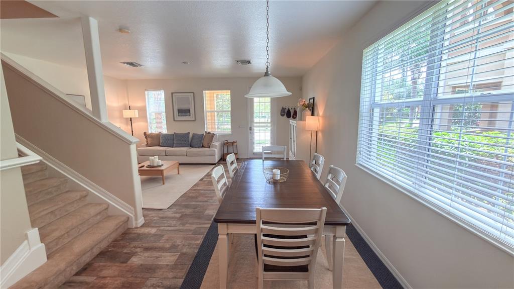 A dining area with a wooden table and chairs sits adjacent to a living room — 3880 82ND AVENUE CIRCLE E UNIT 101, SARASOTA, FL