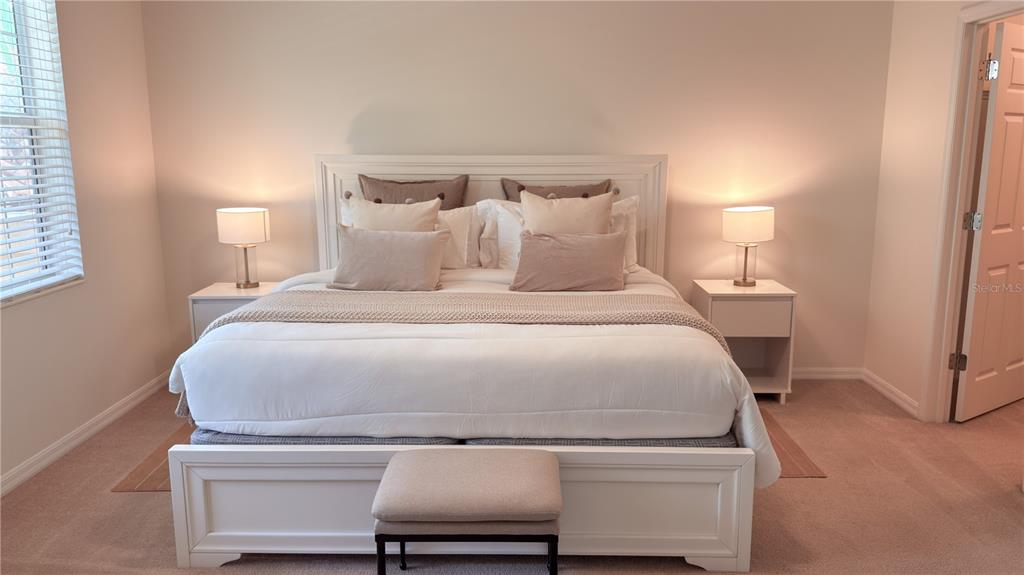 A bedroom features a white bed frame, two nightstands with lamps, and a small ottoman — 3880 82ND AVENUE CIRCLE E UNIT 101, SARASOTA, FL
