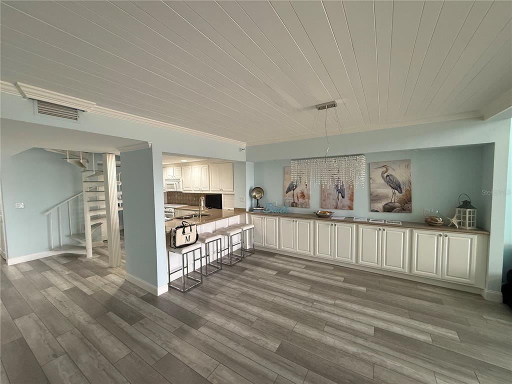 A dining area features light blue walls, wood-look tile flooring, white cabinetry, and a spiral staircase — 19700 GULF BOULEVARD UNIT 202, INDIAN SHORES, FL