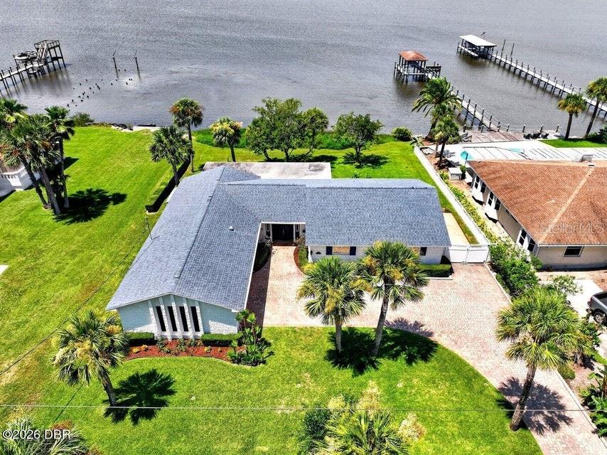 An aerial view shows a waterfront house with a gray roof, brick driveway, and dock — 448 RIVERSIDE DRIVE, ORMOND BEACH, FL