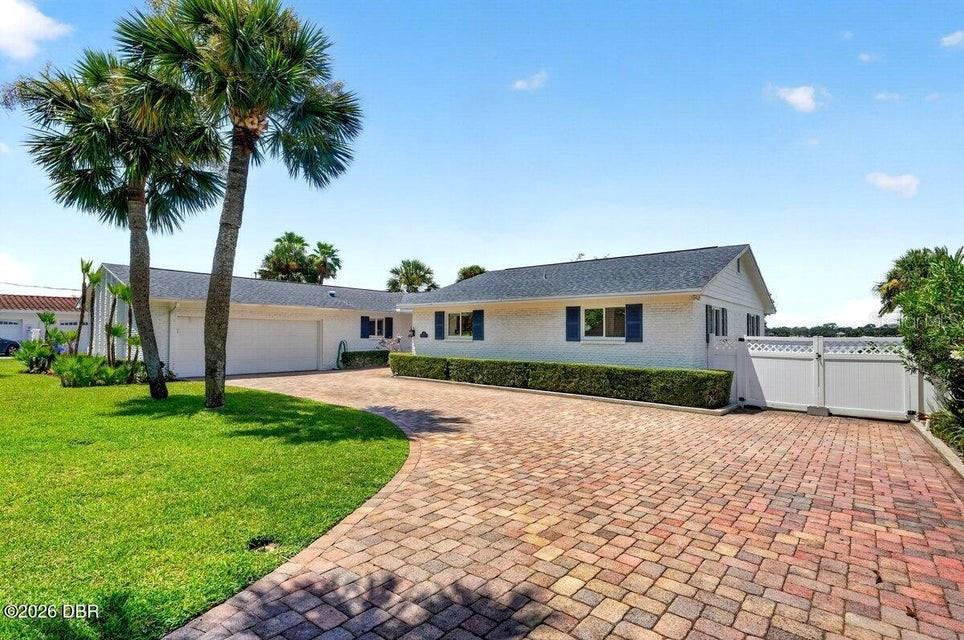 A single-story white brick house features a paved driveway, palm trees, and a white fence — 448 RIVERSIDE DRIVE, ORMOND BEACH, FL