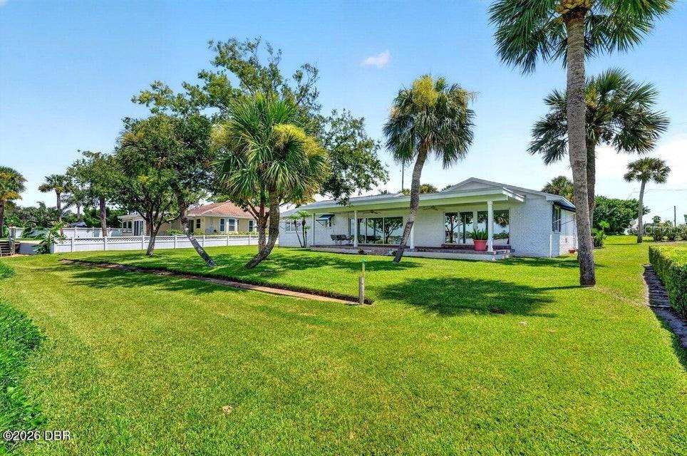 A white single-story house sits on a grassy lawn with several palm trees — 448 RIVERSIDE DRIVE, ORMOND BEACH, FL