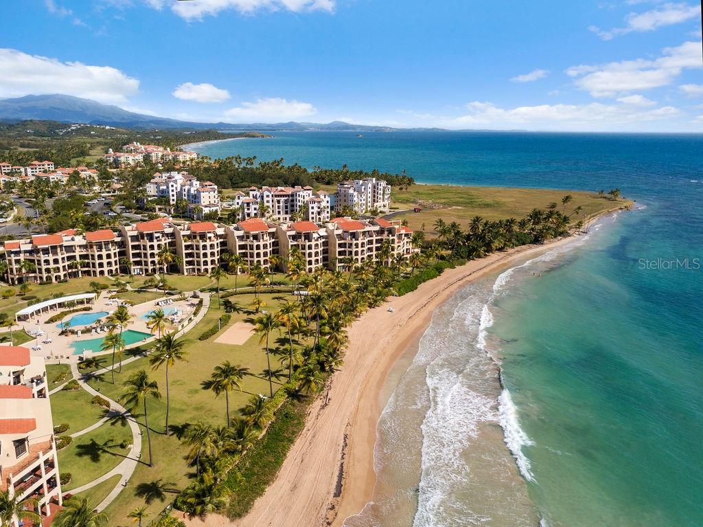 An aerial view shows a beachfront resort complex with swimming pools and palm trees — 190 CANDELERO DRIVE UNIT 175, HUMACAO, PR