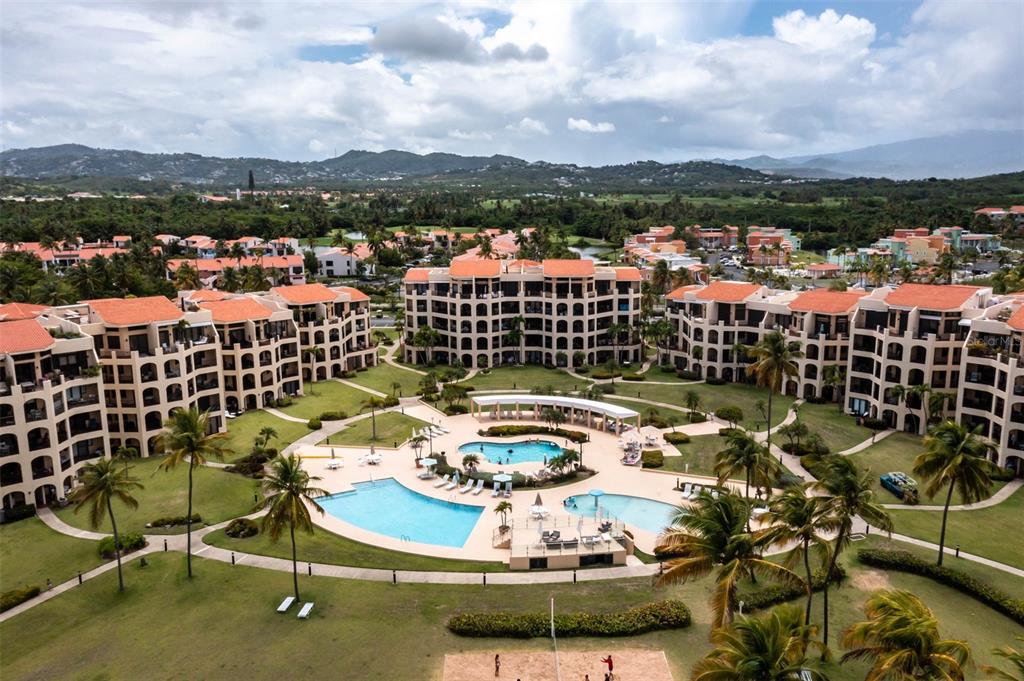 An aerial view of a resort complex featuring multiple buildings, swimming pools, and palm trees — 190 CANDELERO DRIVE UNIT 175, HUMACAO, PR