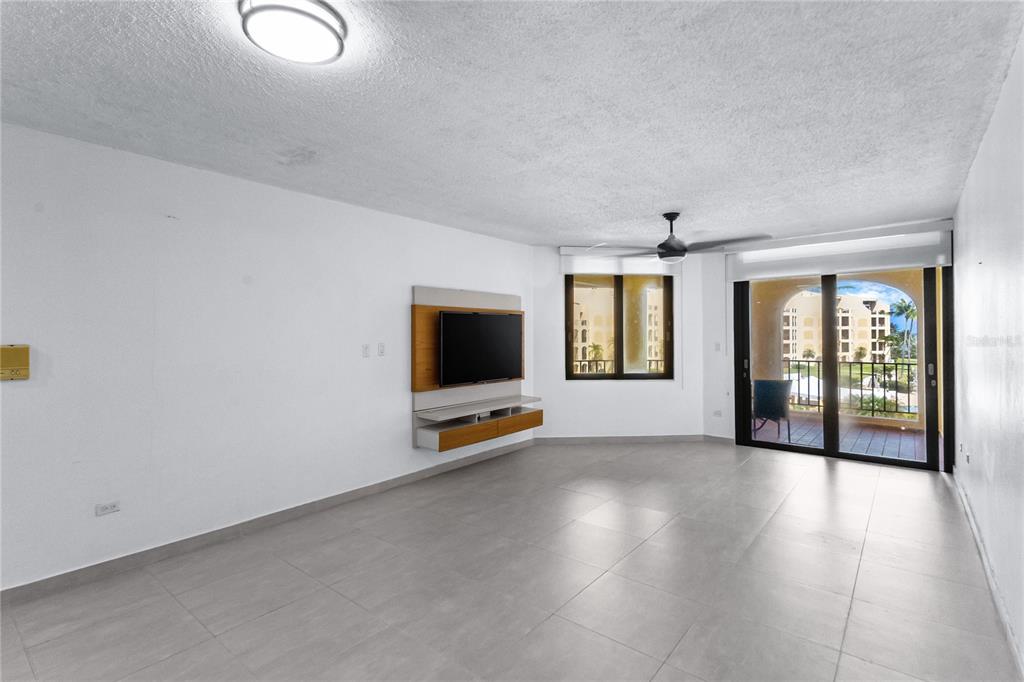A living room with light tile floors, a wall-mounted television, and a sliding glass door — 190 CANDELERO DRIVE UNIT 175, HUMACAO, PR