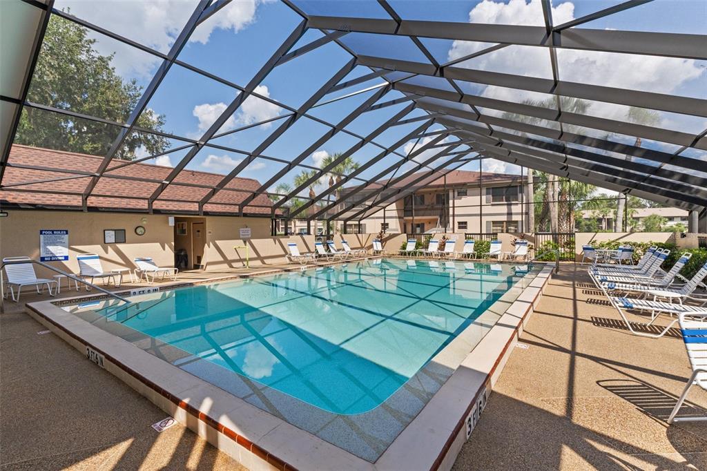 A rectangular swimming pool is enclosed by a screened lanai with lounge chairs on the deck — 19505 QUESADA AVENUE UNIT SS201, PORT CHARLOTTE, FL