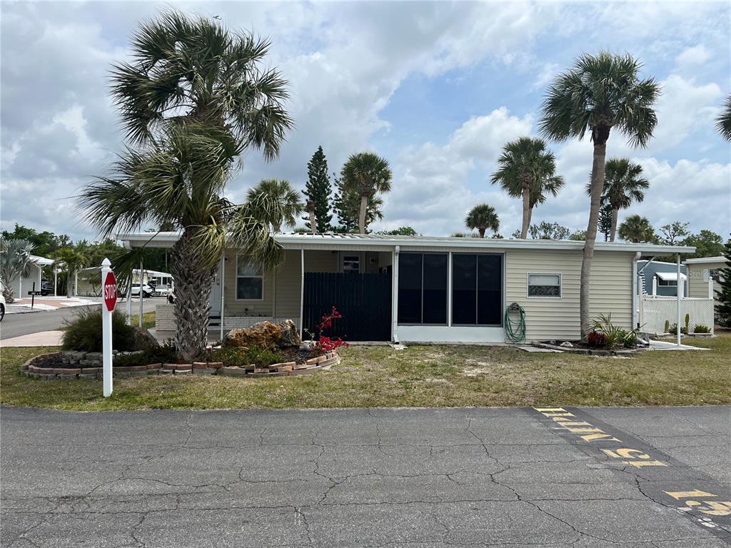 A single-story manufactured home with a screened porch and palm trees in the front yard — 530 VIA VENETO, VENICE, FL