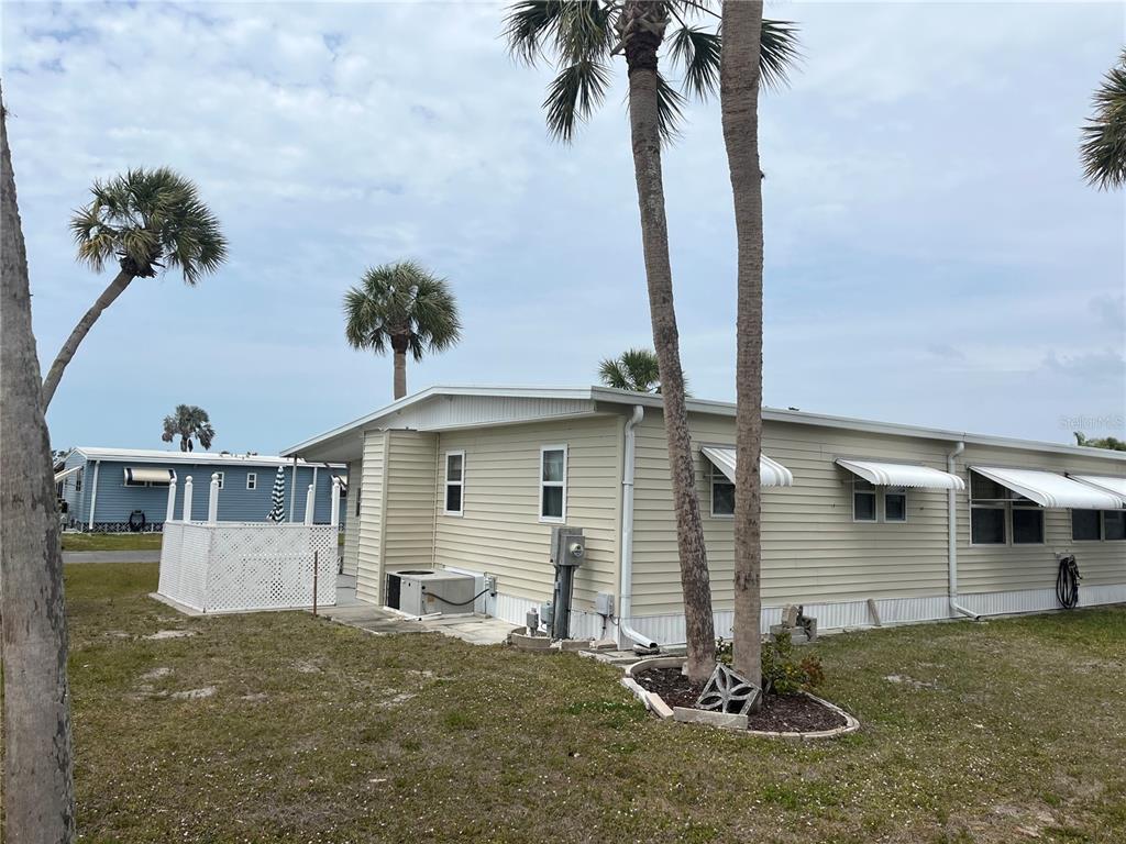 A light-colored mobile home with vinyl siding, metal window awnings, and palm trees outside — 530 VIA VENETO, VENICE, FL
