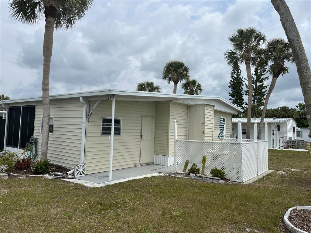 The exterior of a light-colored mobile home features a lattice-enclosed patio and several palm trees — 530 VIA VENETO, VENICE, FL
