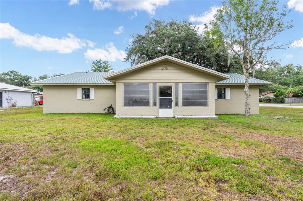 The exterior of a single-story house features a metal roof and a screened-in porch — 6480 SE 42ND COURT, OCALA, FL