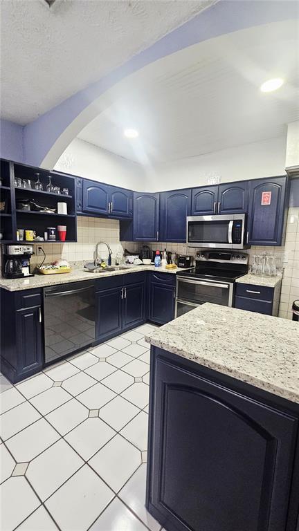 A kitchen with dark blue cabinets, granite countertops, and white tiled flooring — 7714 DELEUIL AVENUE, TAMPA, FL