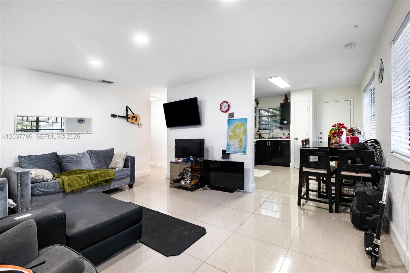 A living room with tile floors, a grey sofa, and an adjacent kitchen area — 1519 NW 40th St # 1, Miami FL 33142, MIAMI, FL