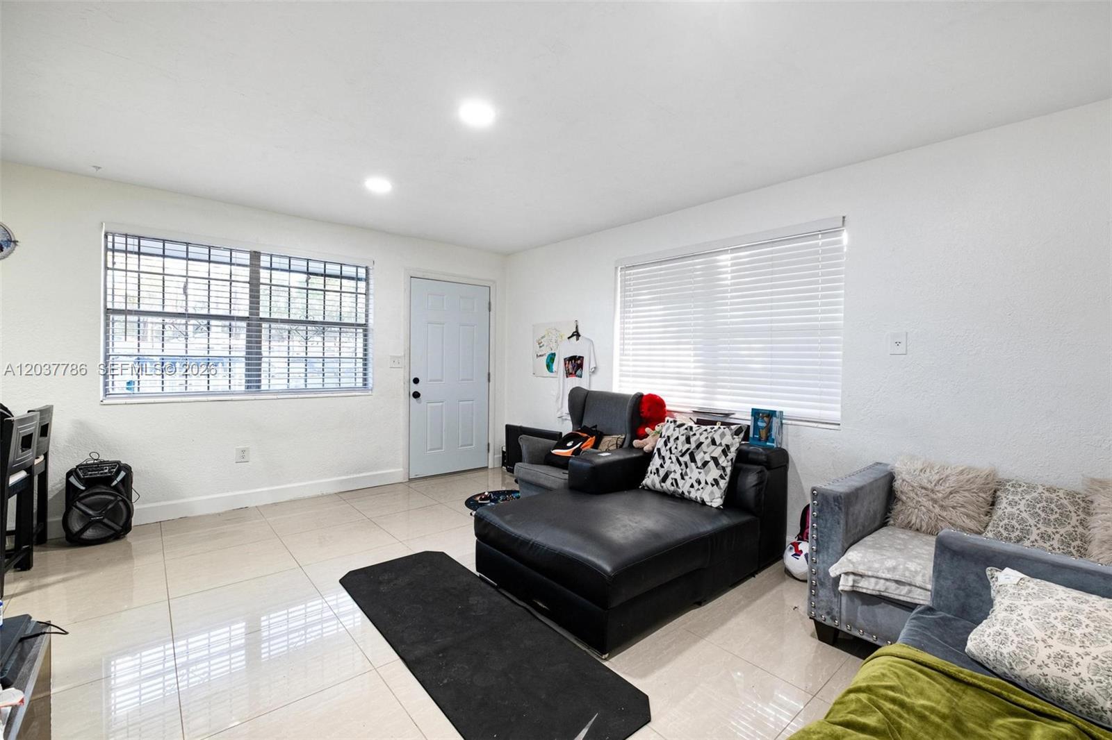 A living room features white walls, tile flooring, a front door, and two sofas — 1519 NW 40th St # 1, Miami FL 33142, MIAMI, FL