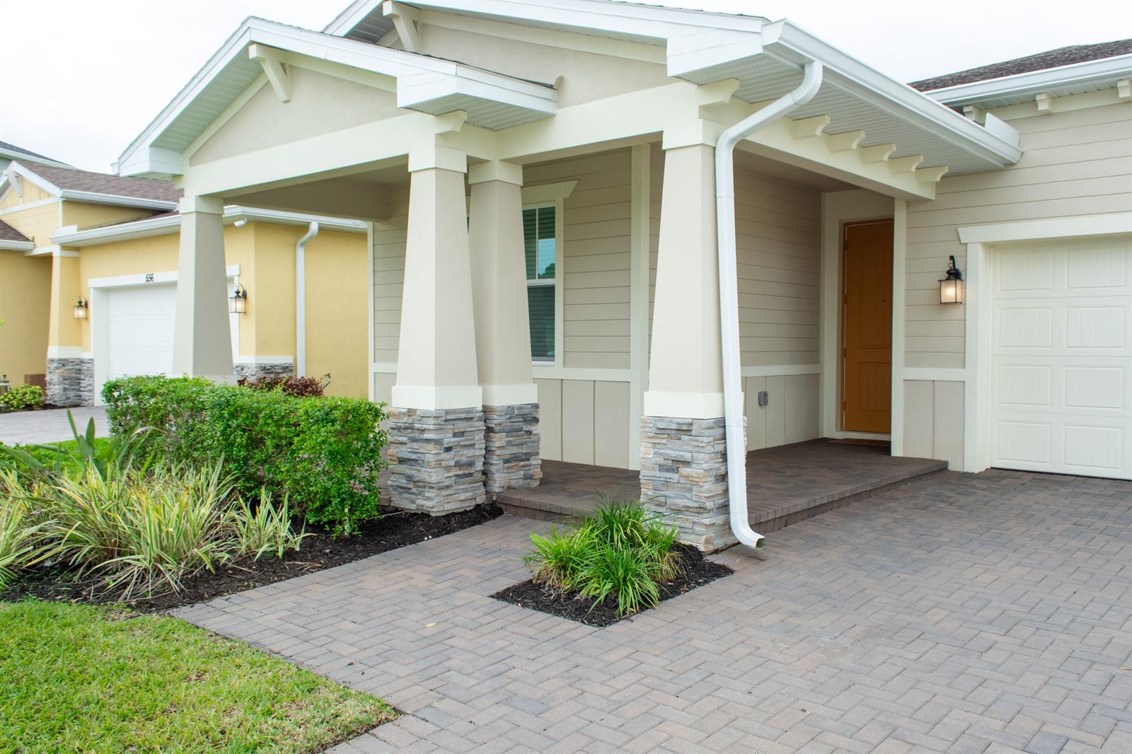 A beige house exterior features a stone-based porch, a paved driveway, and a front door — 560 Veridian Circle NW, Palm Bay FL 32907, PALM BAY, FL
