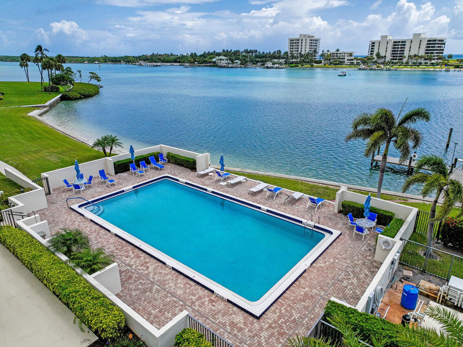 An elevated view of a rectangular swimming pool on a brick patio overlooking the water — 19800 Sandpointe Bay Drive # 512, Tequesta FL 33469, TEQUESTA, FL
