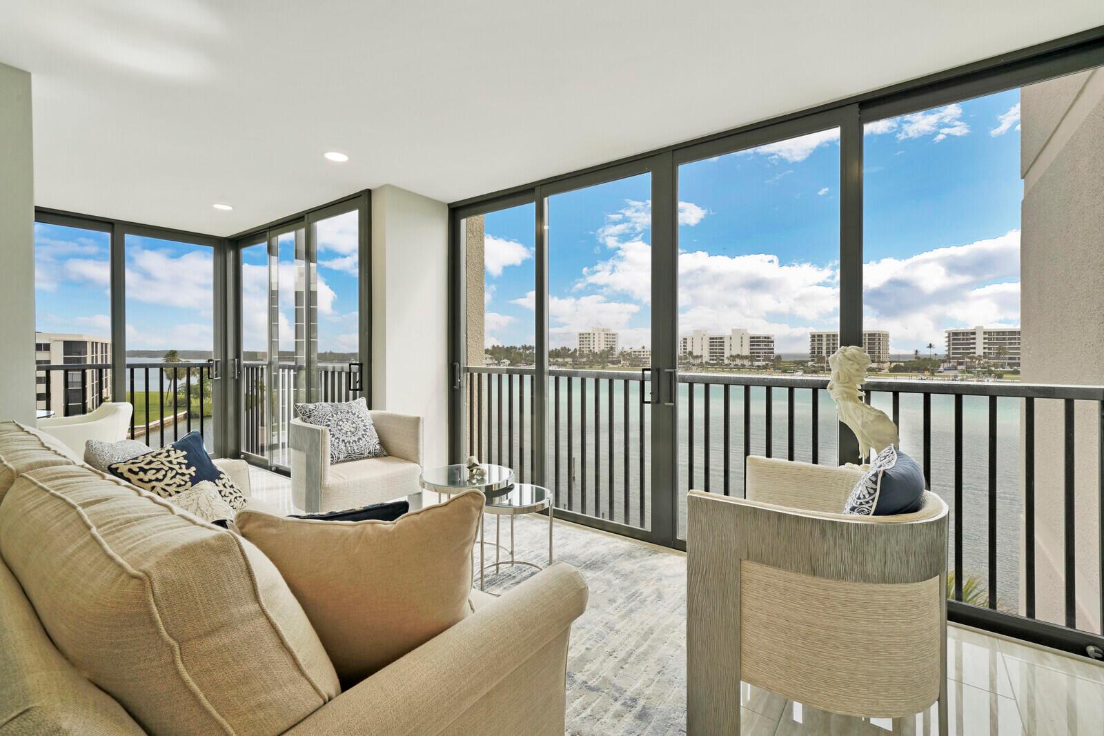 A sunlit living room features floor-to-ceiling windows with a view of the water — 19800 Sandpointe Bay Drive # 512, Tequesta FL 33469, TEQUESTA, FL