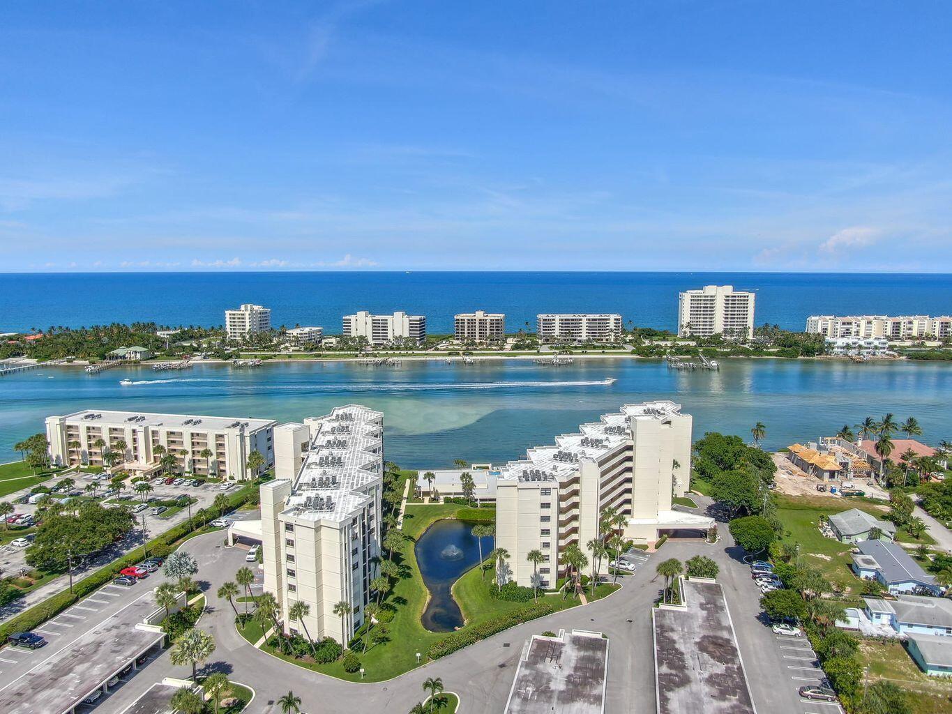An aerial view shows two high-rise apartment buildings near a pond, waterway, and the ocean — 19800 Sandpointe Bay Drive # 512, Tequesta FL 33469, TEQUESTA, FL