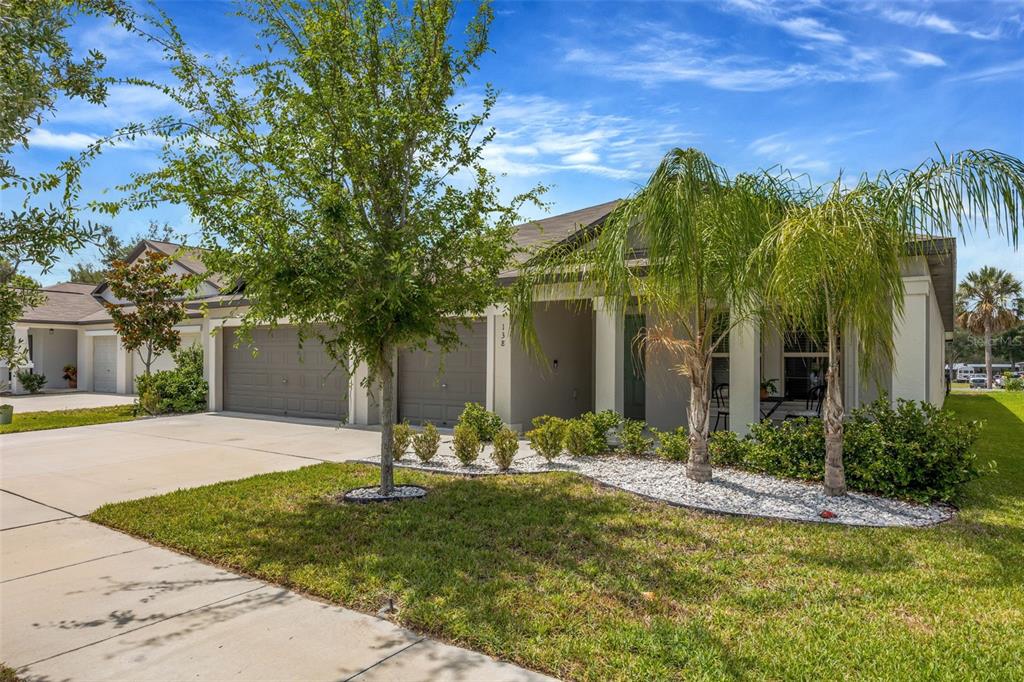 A single-story house with a two-car garage, palm trees, and a landscaped front yard — 138 RAIN BERRY AVENUE, RUSKIN, FL