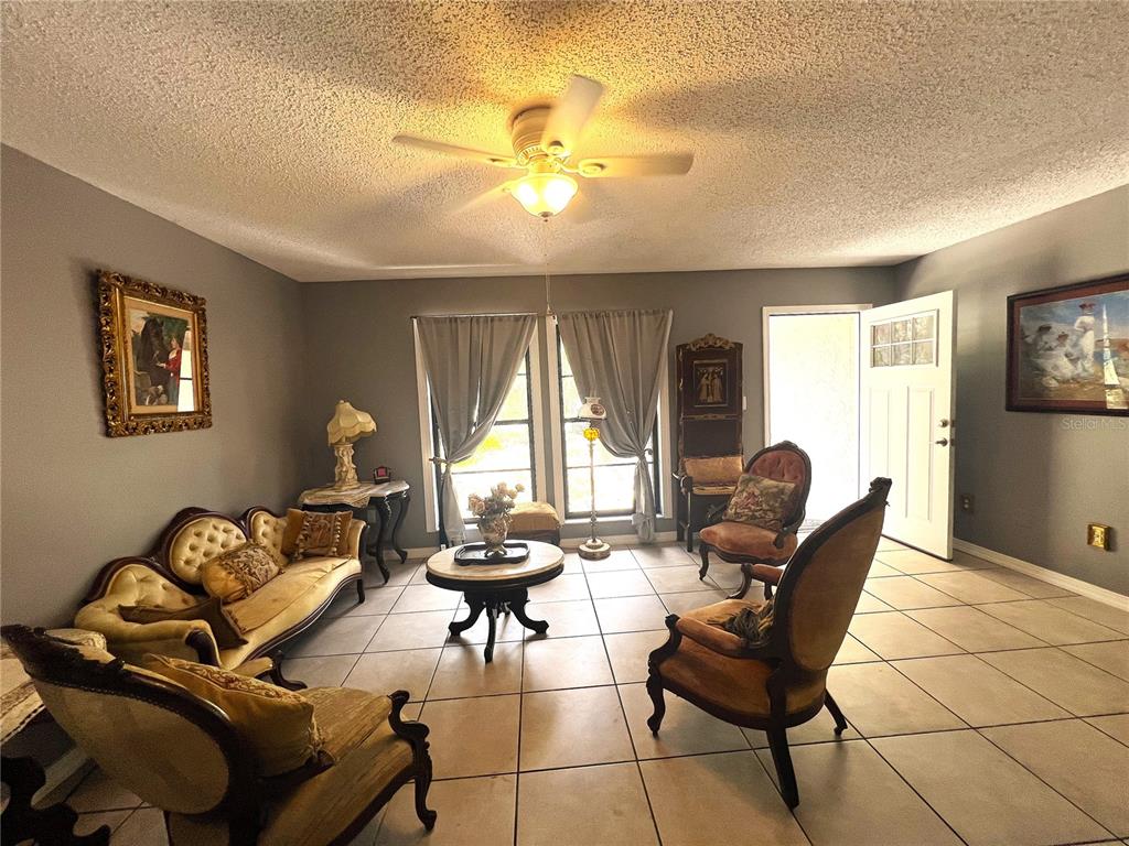 A living room features tile flooring, a ceiling fan, and traditional-style furniture — 220 NE 11TH STREET, CRYSTAL RIVER, FL